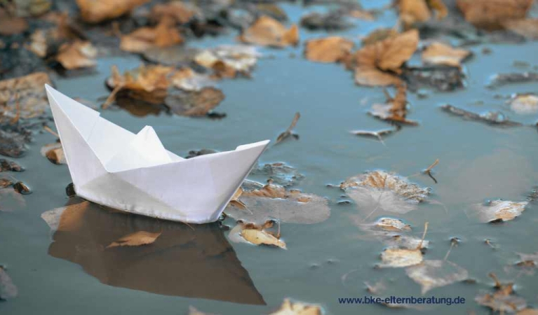 Ein Papierboot in einer Pfütze